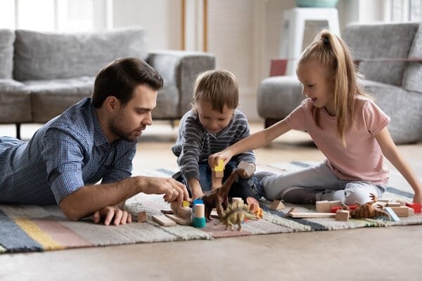 Young father playing with bricks and toys with little kids