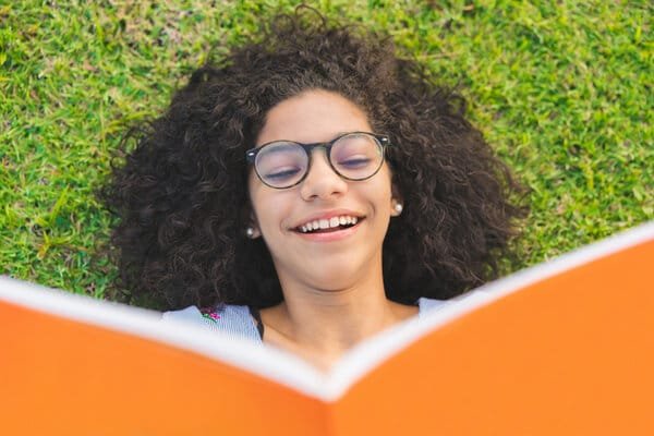 Girl lying on the grass and reading a book