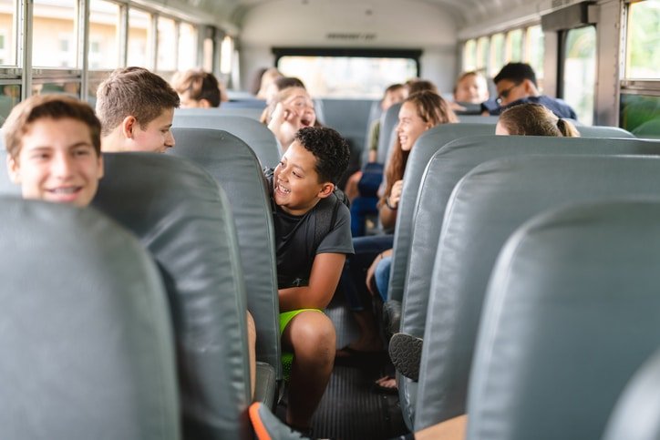 Elementary age students riding school bus