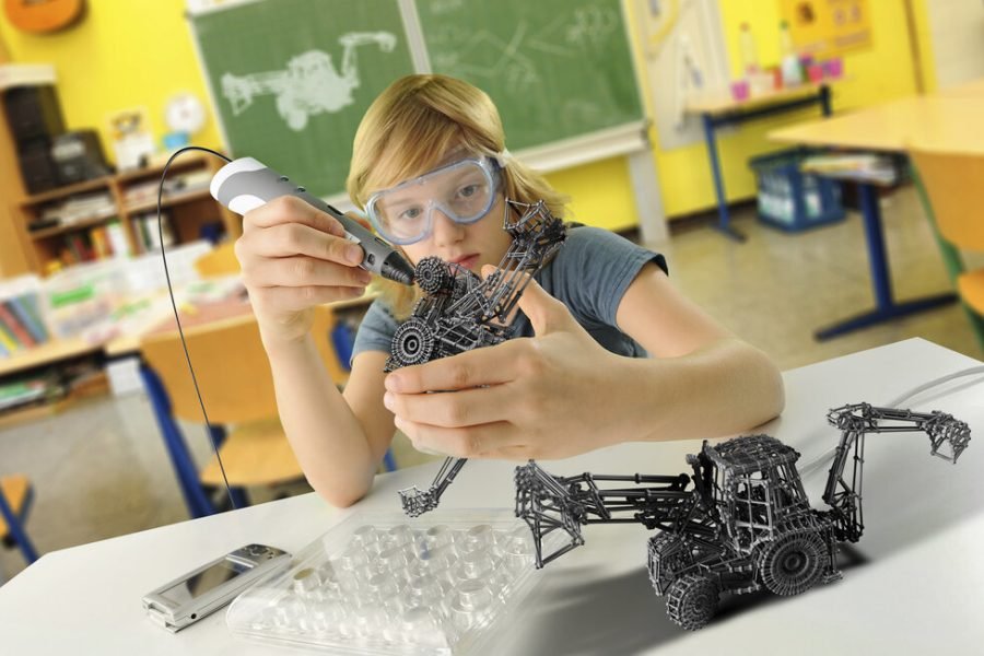 Boy with digital pen and 3D model of excavator in classroom