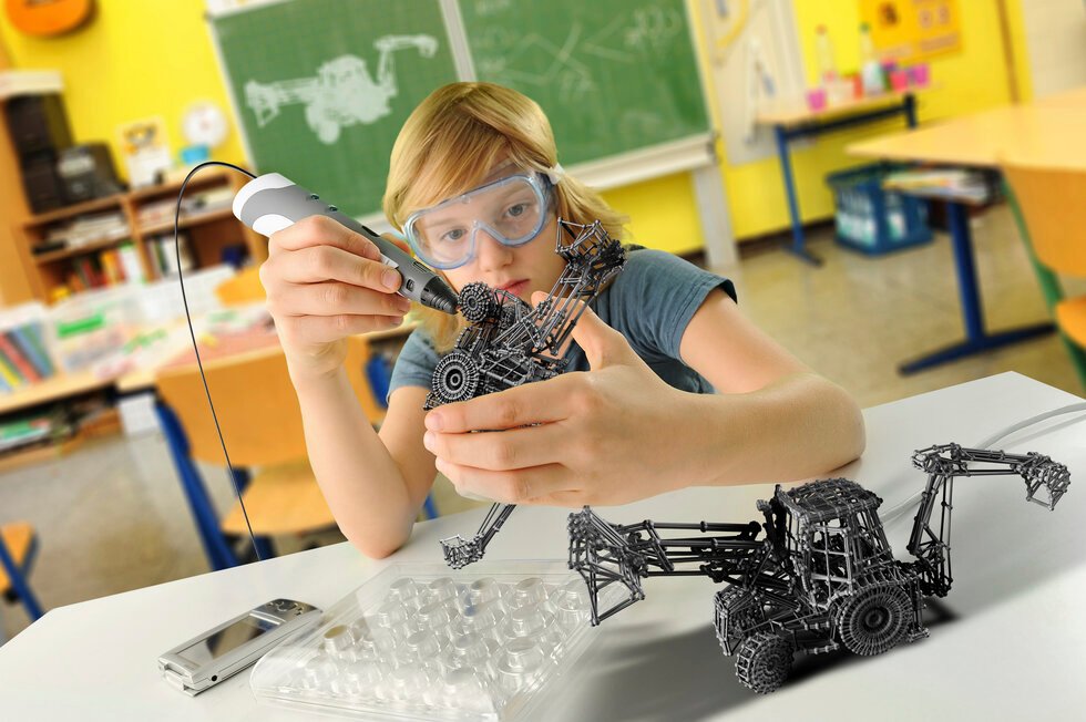 Boy with digital pen and 3D model of excavator in classroom